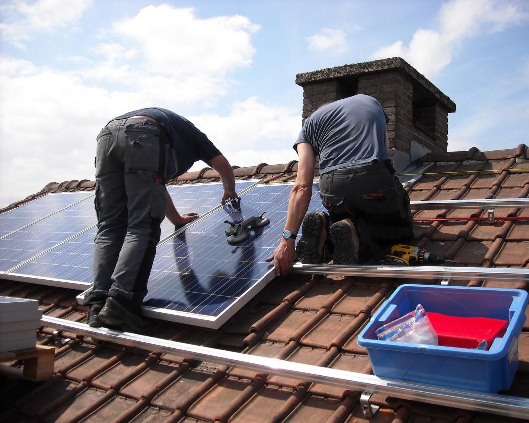 Twee mannen monteren zonnepanelen op een dak
